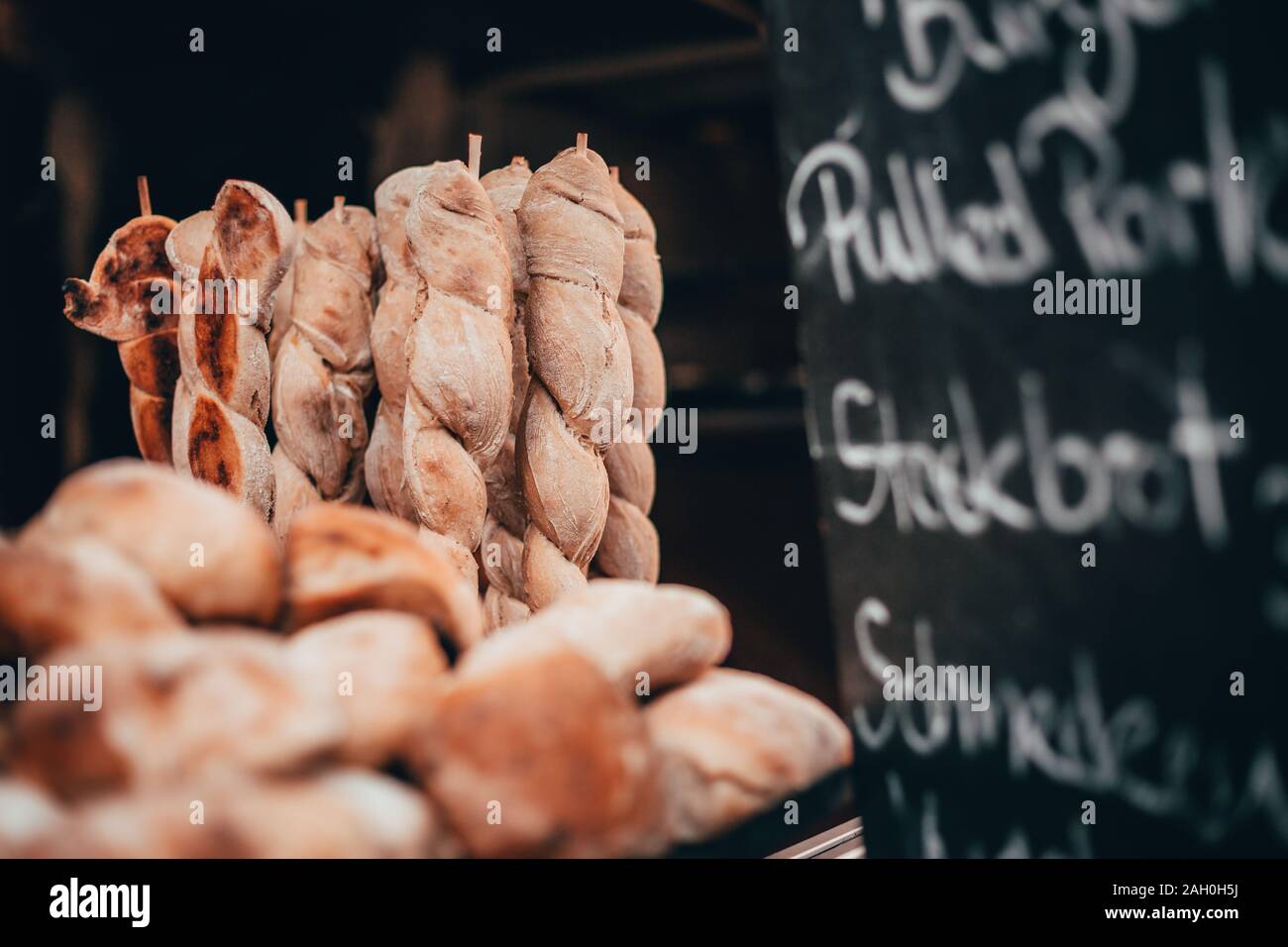 bread on a stick and red burger buns baked in a wood stove with pulled pork Chocolate market chocolART in tübingen, Germany with christmas booths and Stock Photo