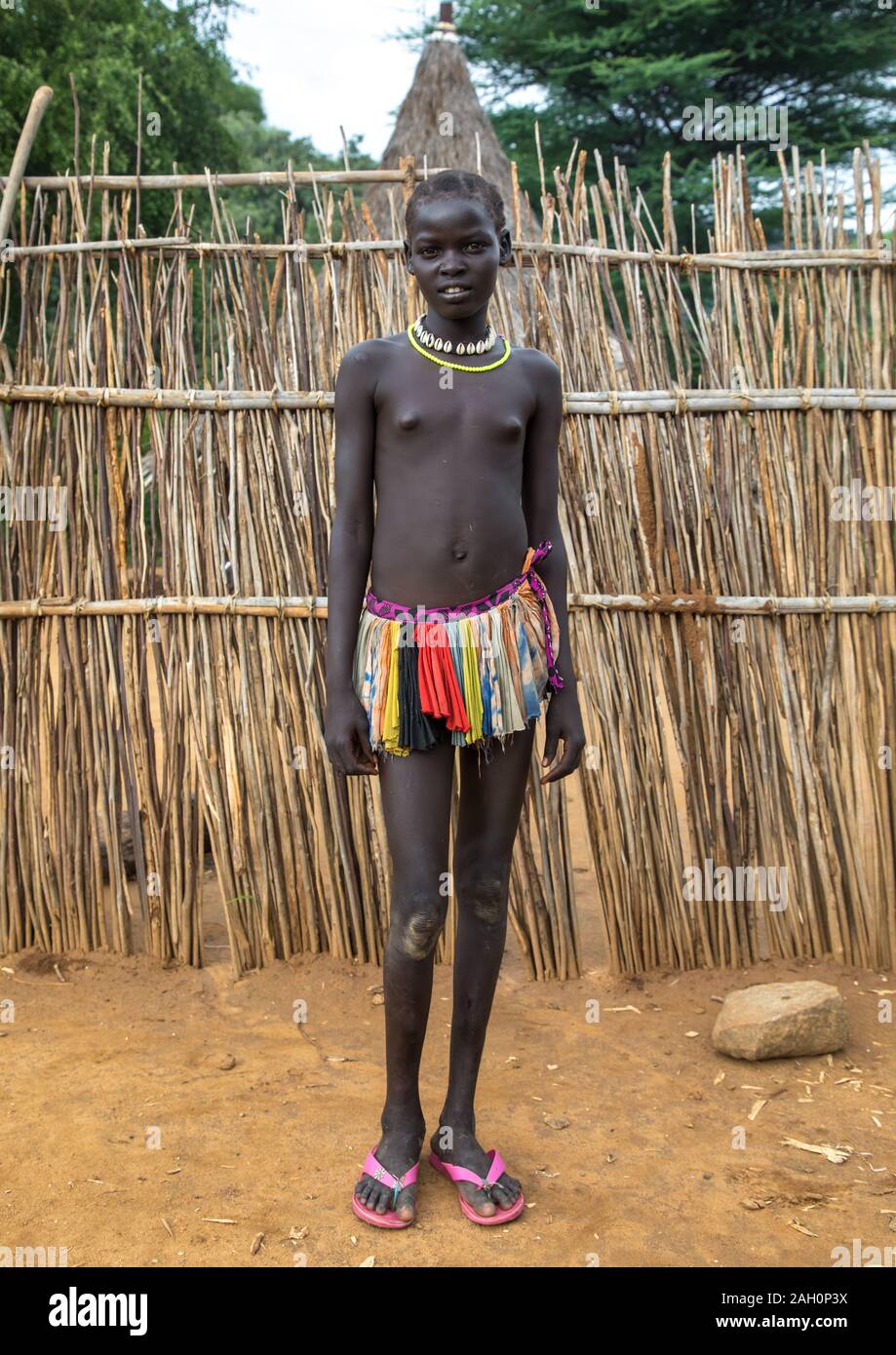 Larim tribe teenage girl in front of her traditional house, Boya Mountains, Imatong, South Sudan Stock Photo