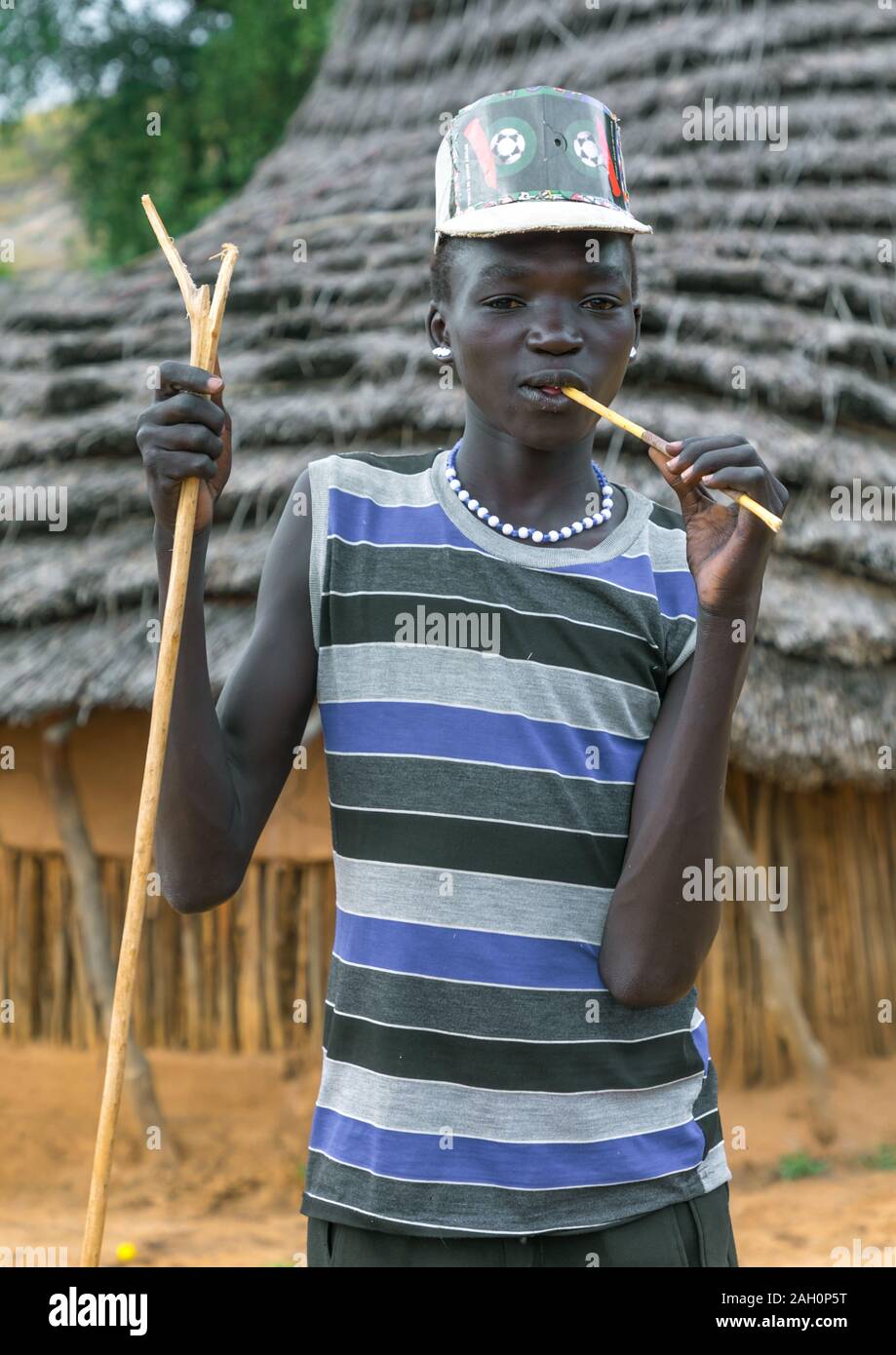 Larim tribe boy with a fashionnable look using a wooden toothbrush, Boya Mountains, Imatong, South Sudan Stock Photo