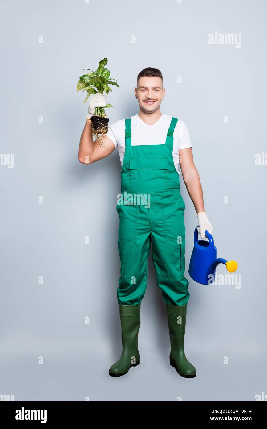 I will save your plant. Full size vertical photo of nice strong arms man hold watering can fresh plant changing pot wear green overall gumboot Stock Photo