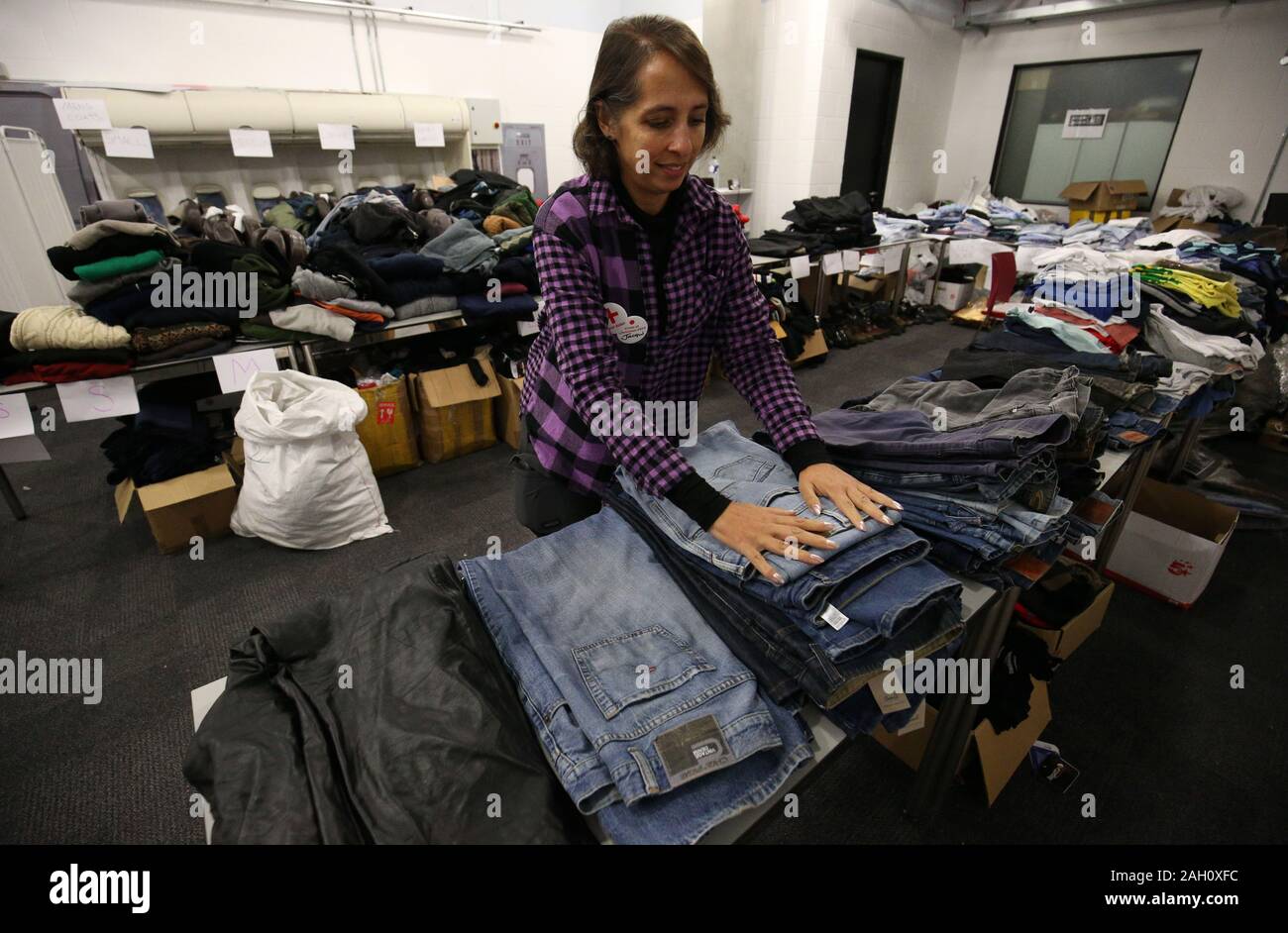 A Crisis volunteer organises items of clothing at a Crisis Christmas centre in London, as the charity opens its doors to homeless people for the festive period. Stock Photo