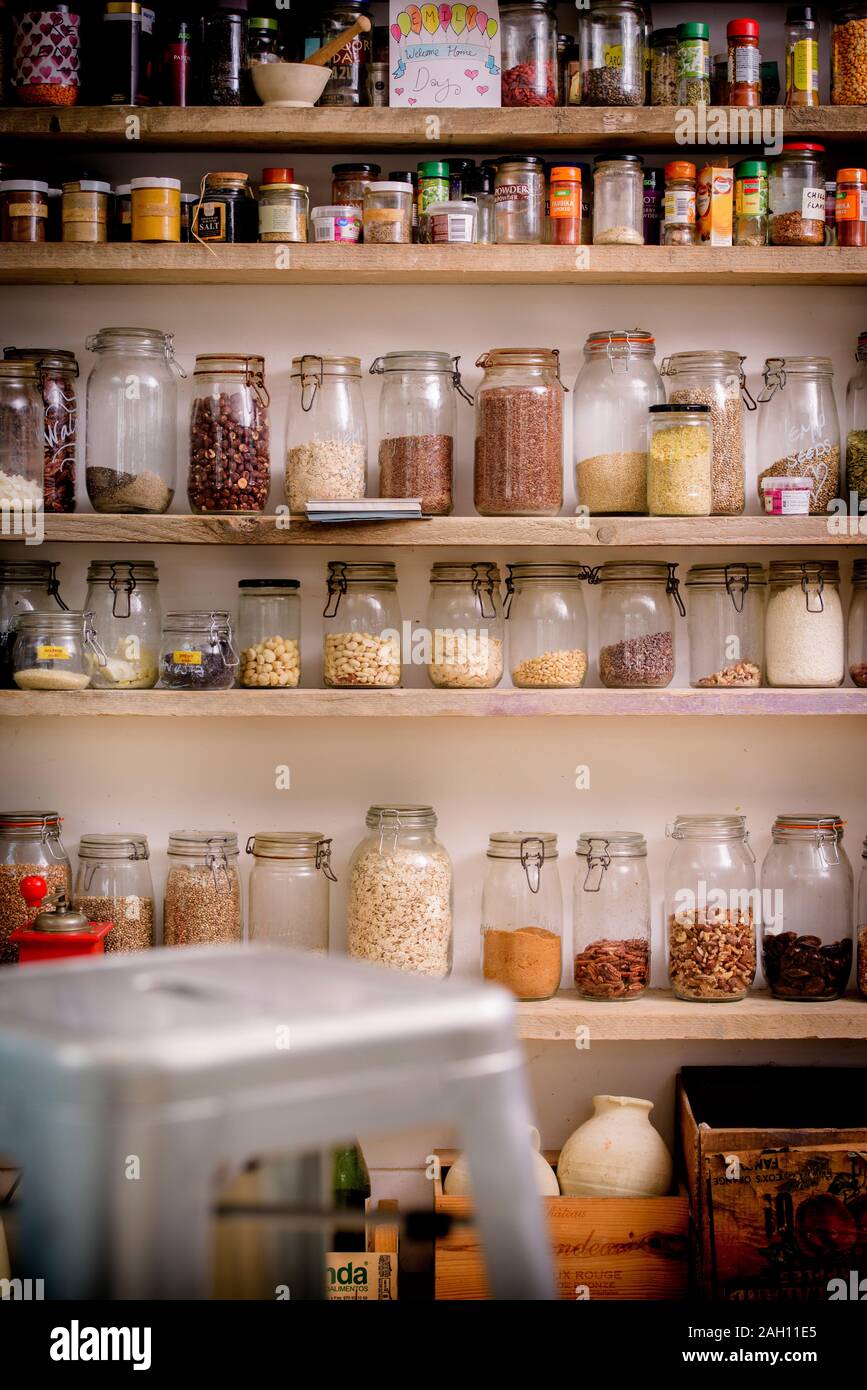 A store cupboard with kilner jars filled with various ingredients like rice, seeds, beans and nuts. Stock Photo