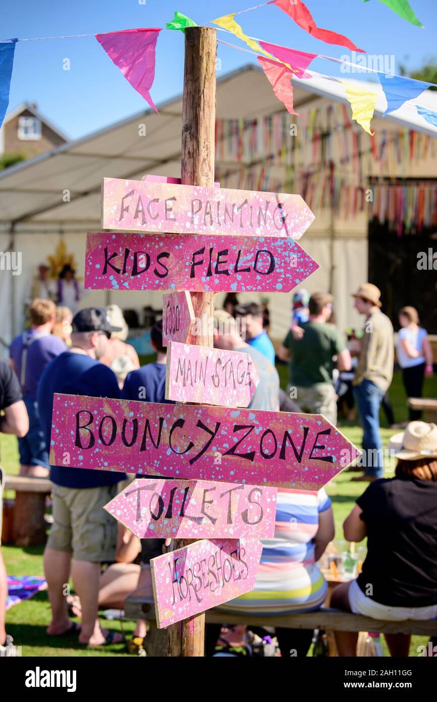 Pink signage at a summer festival pointing the way to various activities and areas. Stock Photo