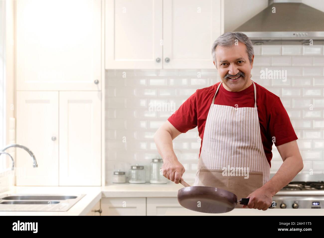 Portrait of a senior man cooking in the kitchen. Stock Photo