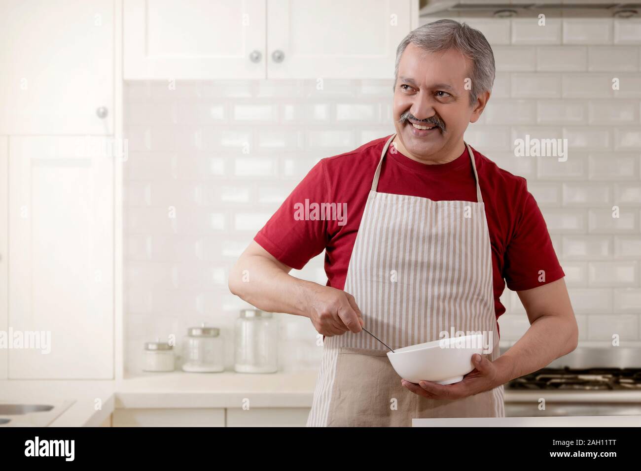 Portrait of a senior man cooking in the kitchen. Stock Photo