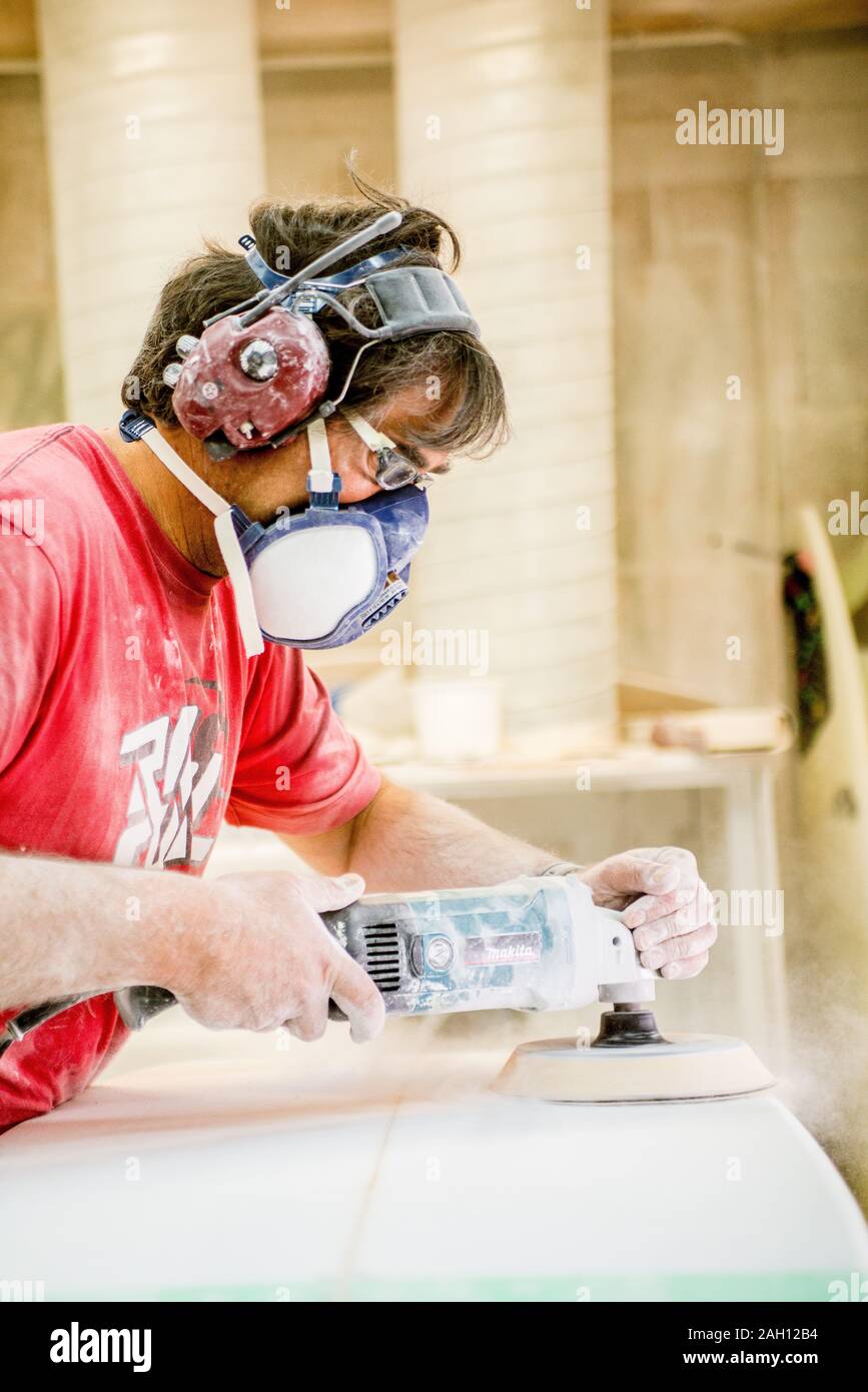 man with mask sanding a surfboard in a dusty shop Stock Photo Alamy