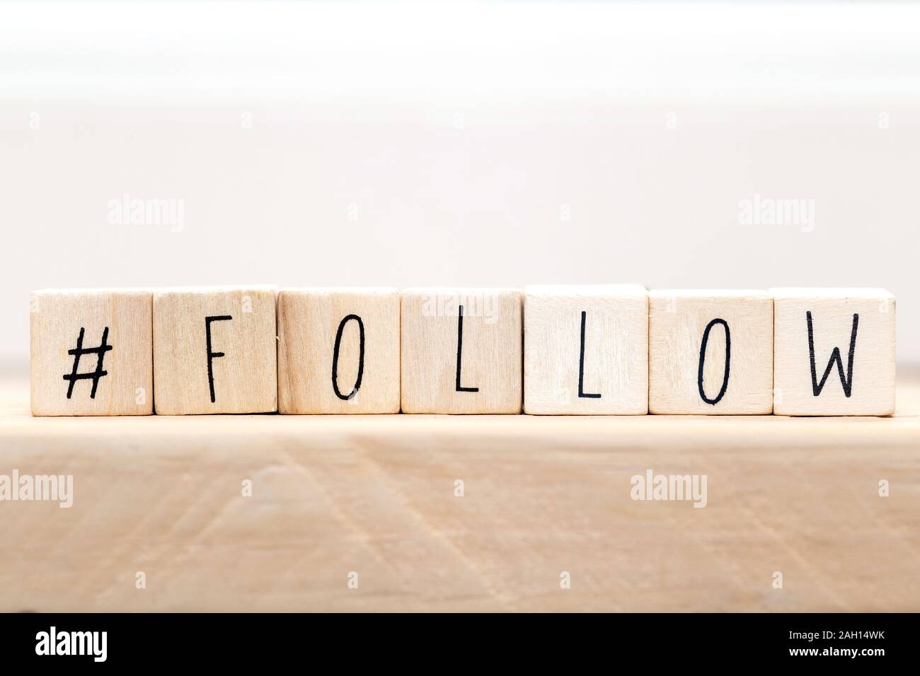 Follow sign made of cubes on a wooden table with Hashtag near white background, socialmedia concept Stock Photo