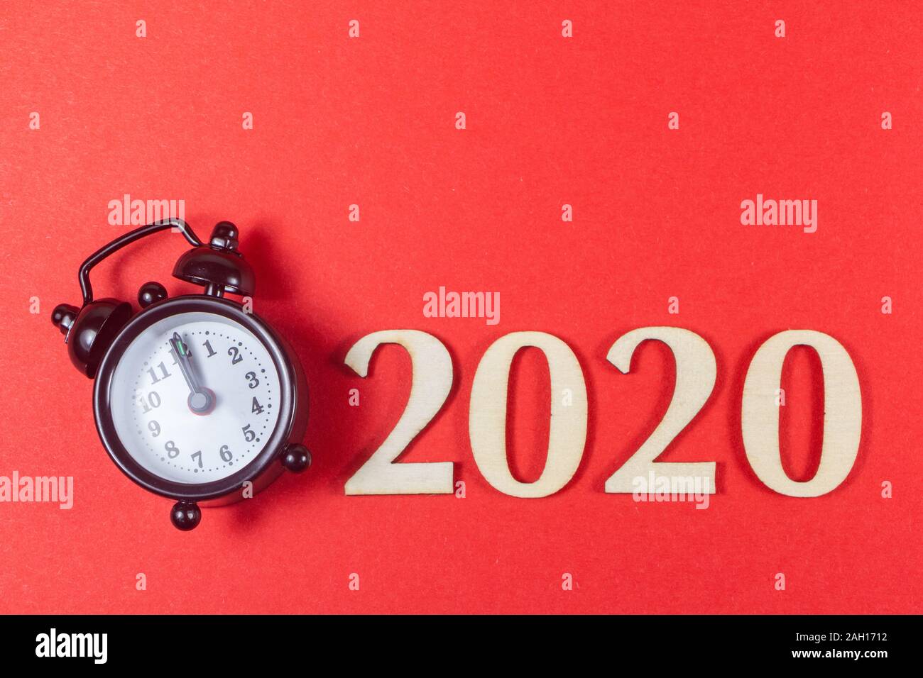 2020 in wooden figures and black alarm clock on red background Stock Photo