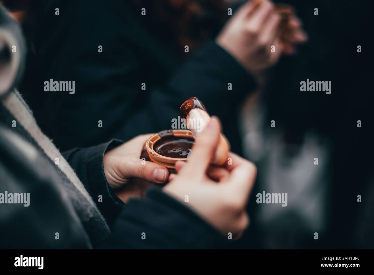 Woman hands eating liquid chocolate on the Chocolate market chocolART in Tübingen, Germany with christmas booths and stalls with many people standing Stock Photo