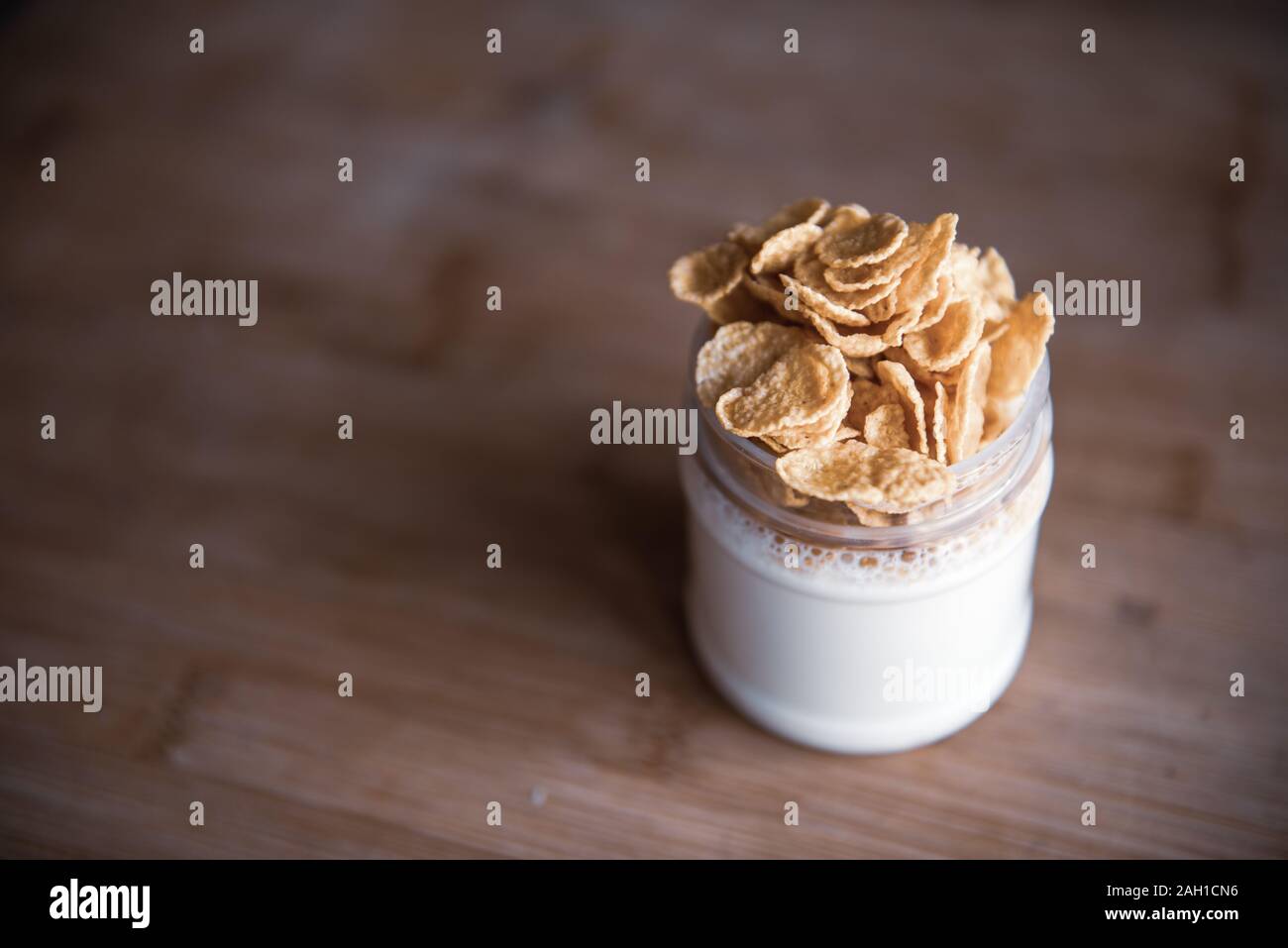 Delicious breakfast - glass jar of yogurt with cornflakes stands on a wooden table with copy space Stock Photo