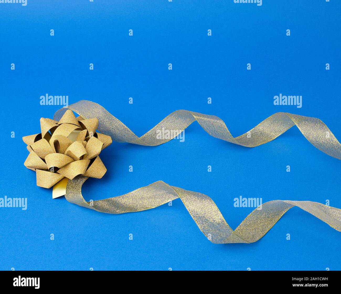 Shiny Golden Satin Ribbon And Bow On A Blue Background Beautiful