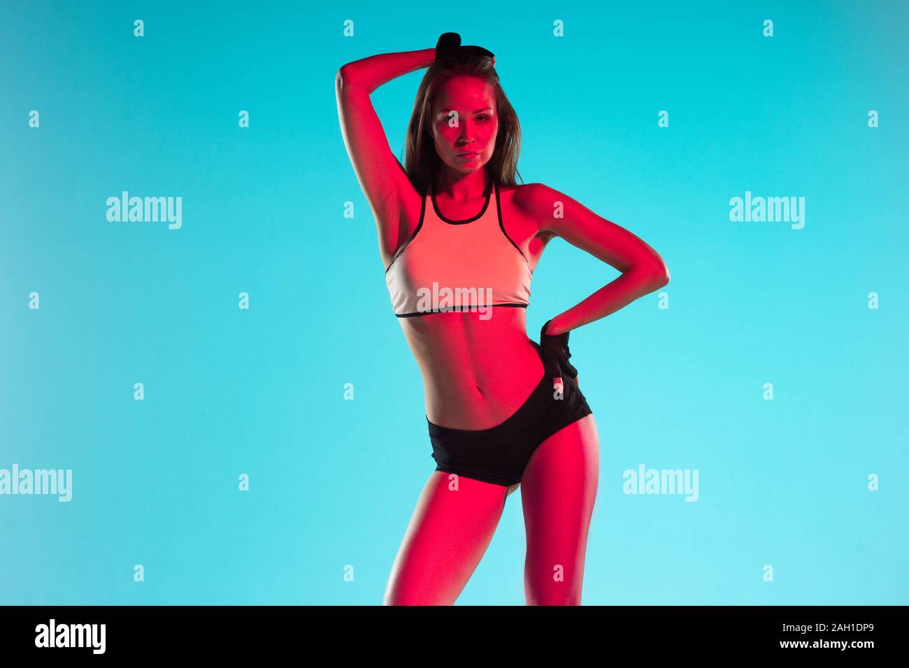 Muscular Young Female Athlete On Blue Background In Neon Muscular Young Female Athlete On Blue Background In Neon