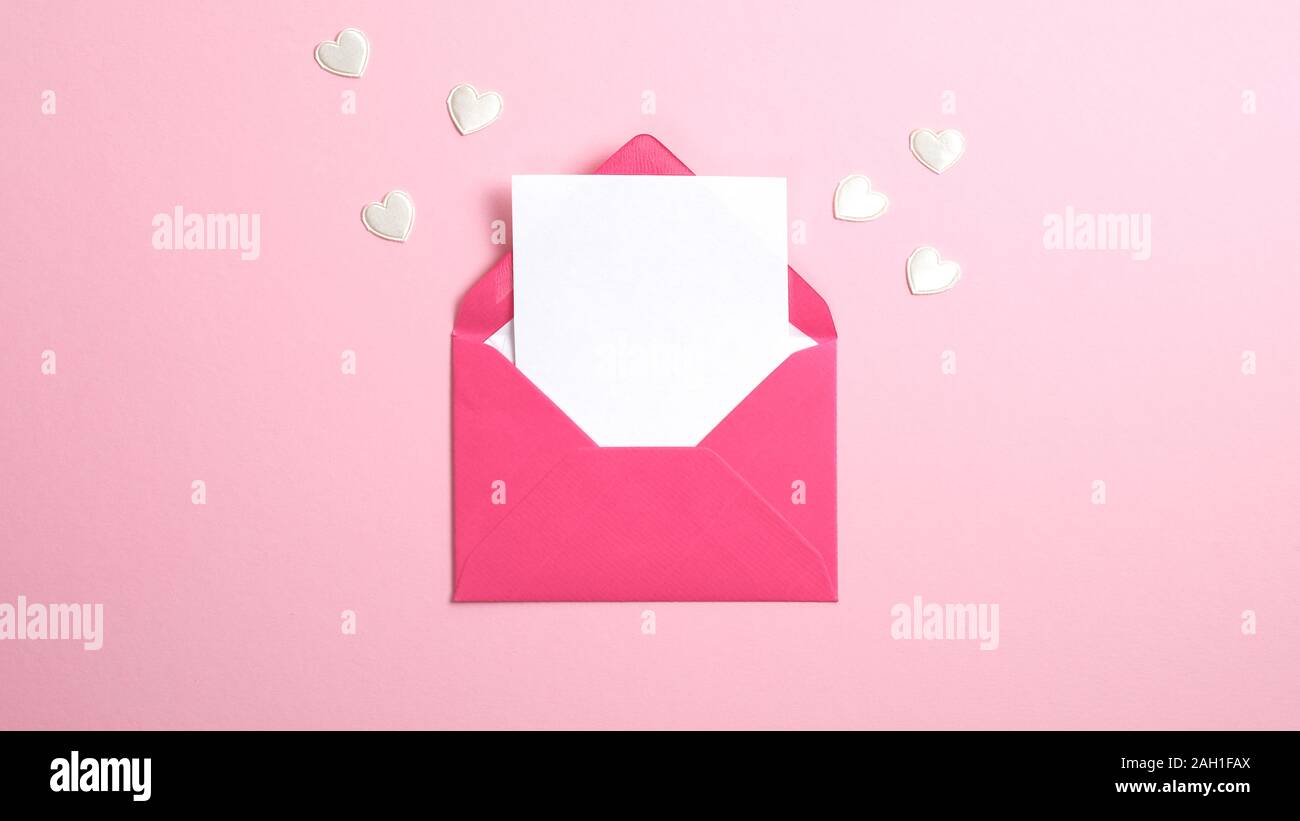 Envelope with blank white paper note inside and Valentine hearts on ...