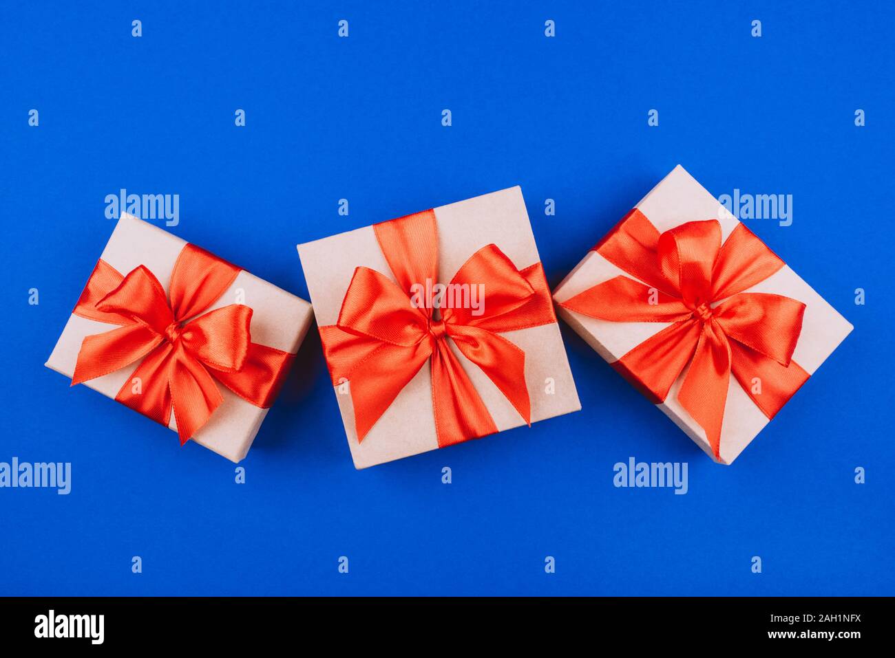 Three cardboard gift boxes with bows on blue background. Stock Photo