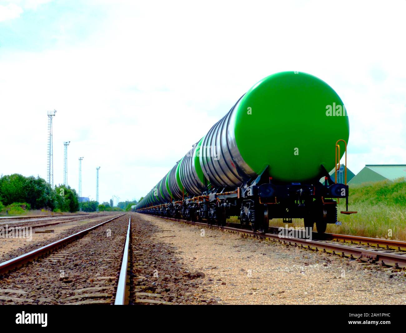 green bio fuel freight trains in railroad station with industrial background in diminishing perspective. tanker train. rail transportation concept. Stock Photo