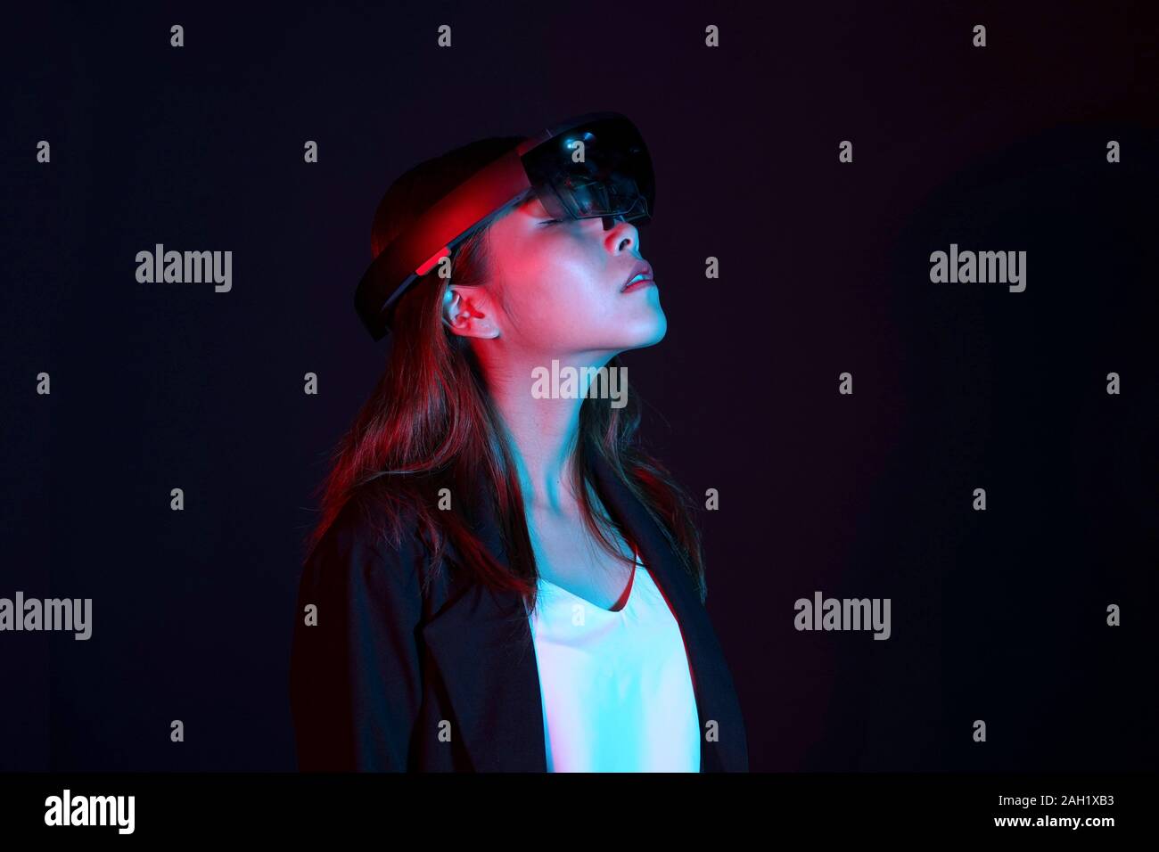 Business woman try vr glasses hololens in the dark room. Portrait of young asian girl experience ar. Future technology and power of feminism concept Stock Photo