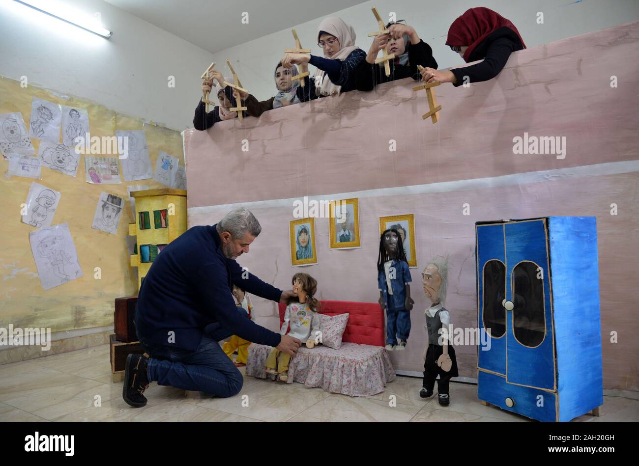 Gaza. 23rd Dec, 2019. Mahdi Karira (Front) and his team members works on their marionettes at his office in Gaza City, on Dec. 23, 2019. Mahdi Karira, a 39-year-old master at making the marionette, spent 6 months on training a group of 8 girls and 2 young men to make puppets and perform puppet theater shows for children, in an attempt to promote the art of puppet theater in the Gaza Strip. Credit: Rizek Abdeljawad/Xinhua/Alamy Live News Stock Photo