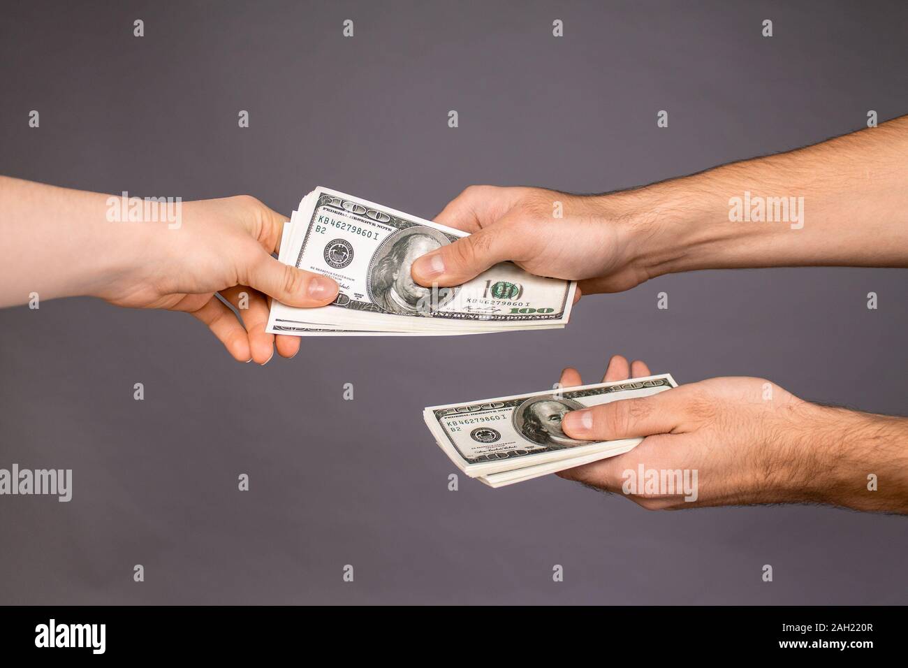 Close up of a guy handing over money for a product or service on a gray background Stock Photo