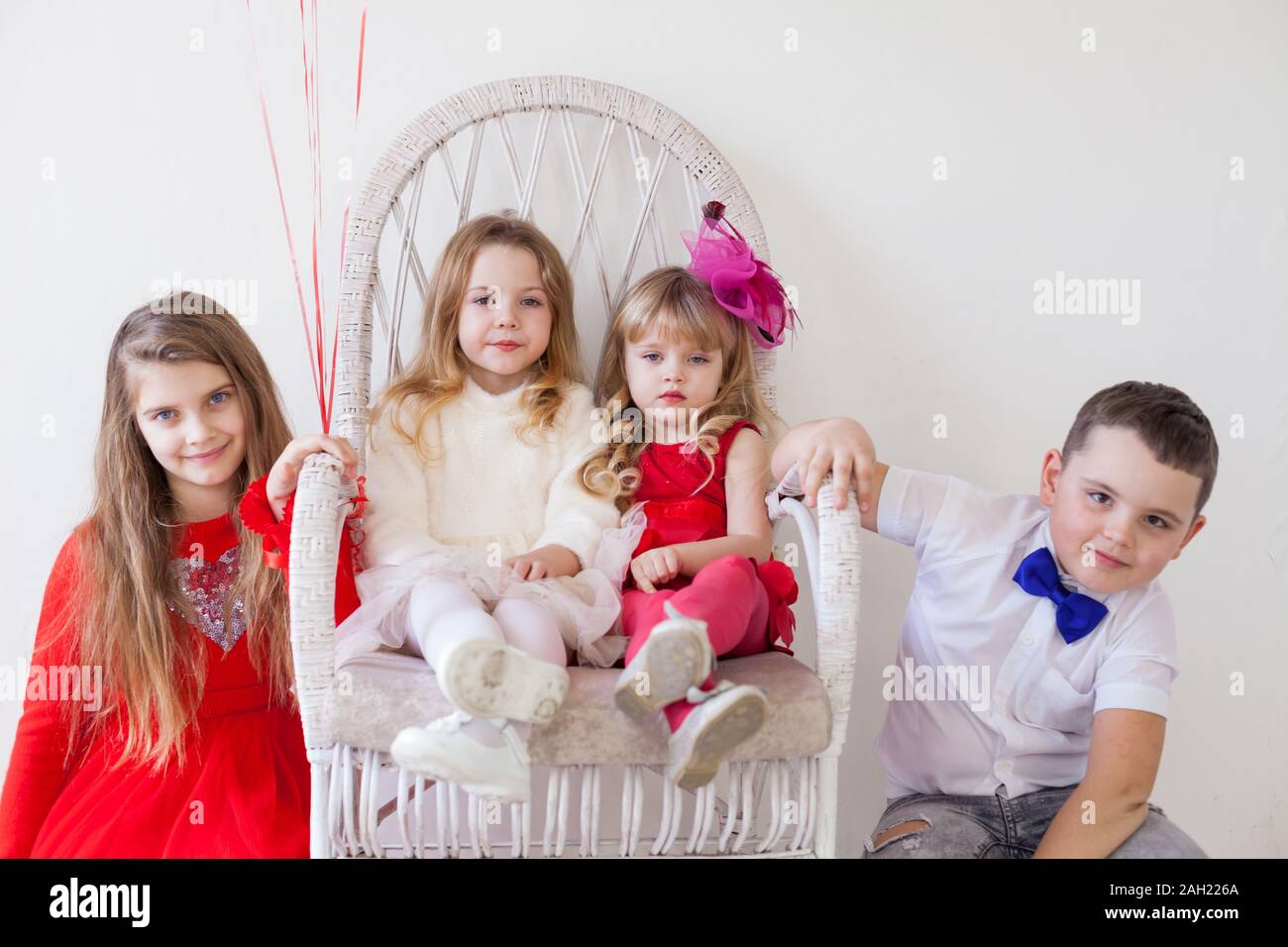 three little girls and a boy sitting at a friends party Stock Photo - Alamy