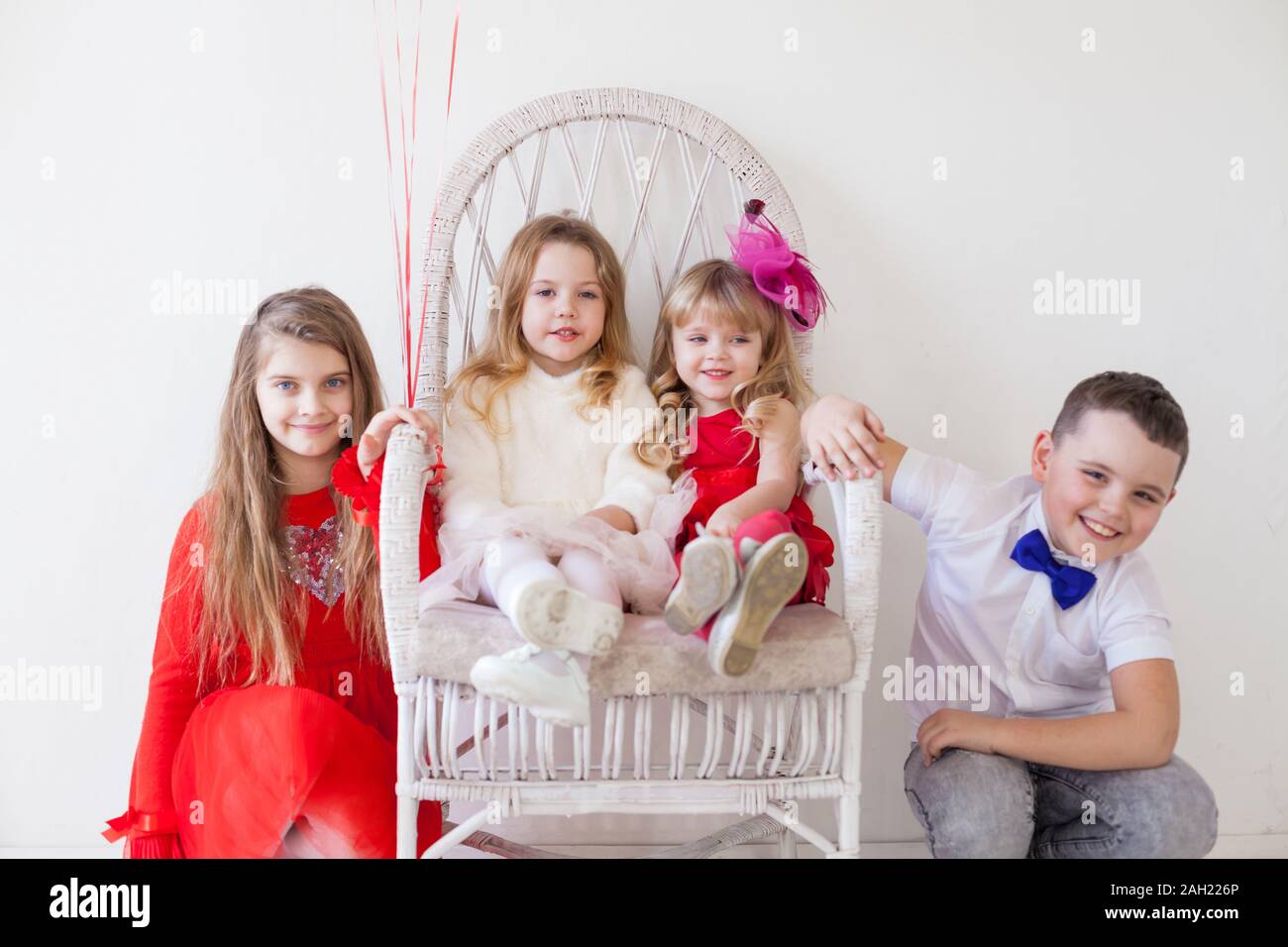 three little girls and a boy sitting at a friends party Stock Photo - Alamy