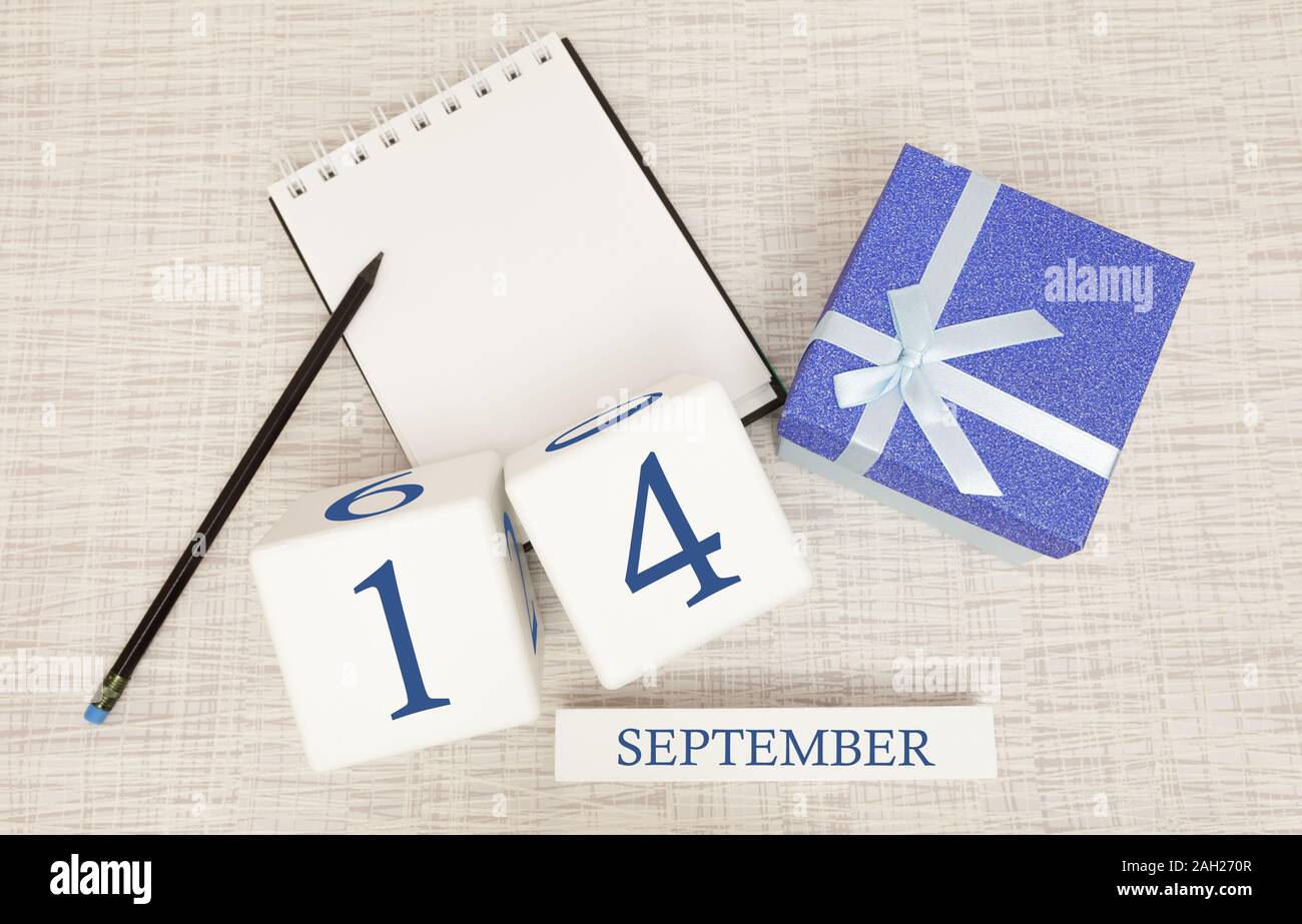 Gift box and wooden calendar with trendy blue numbers, September 14, business planner Stock Photo