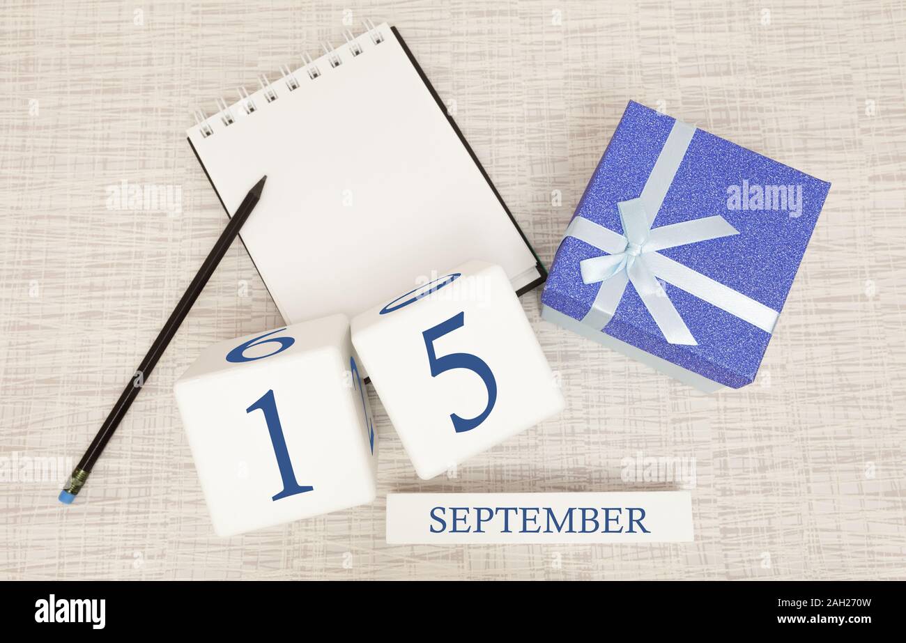 Gift box and wooden calendar with trendy blue numbers, September 15, business planner Stock Photo