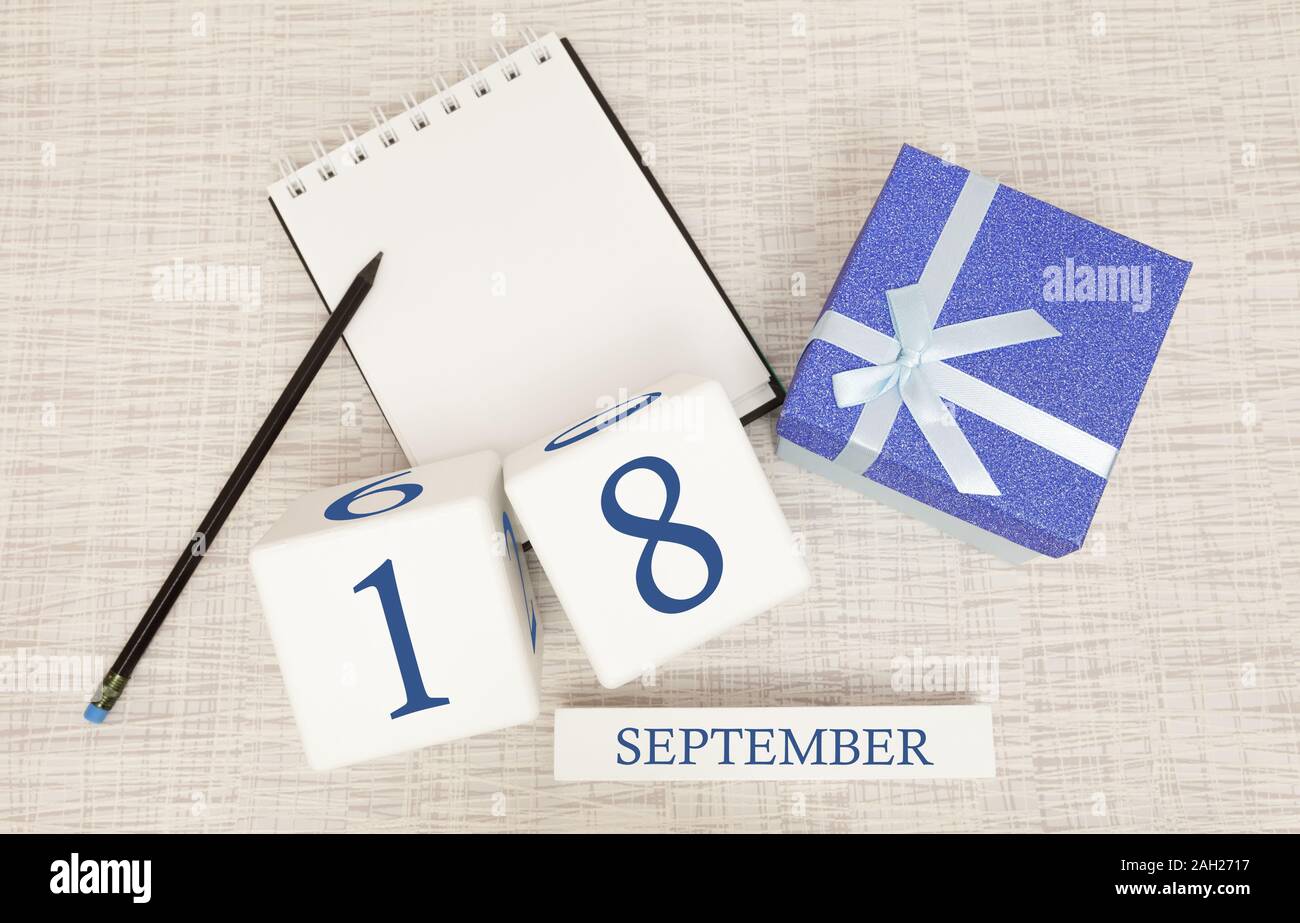 Gift box and wooden calendar with trendy blue numbers, September 18, business planner Stock Photo