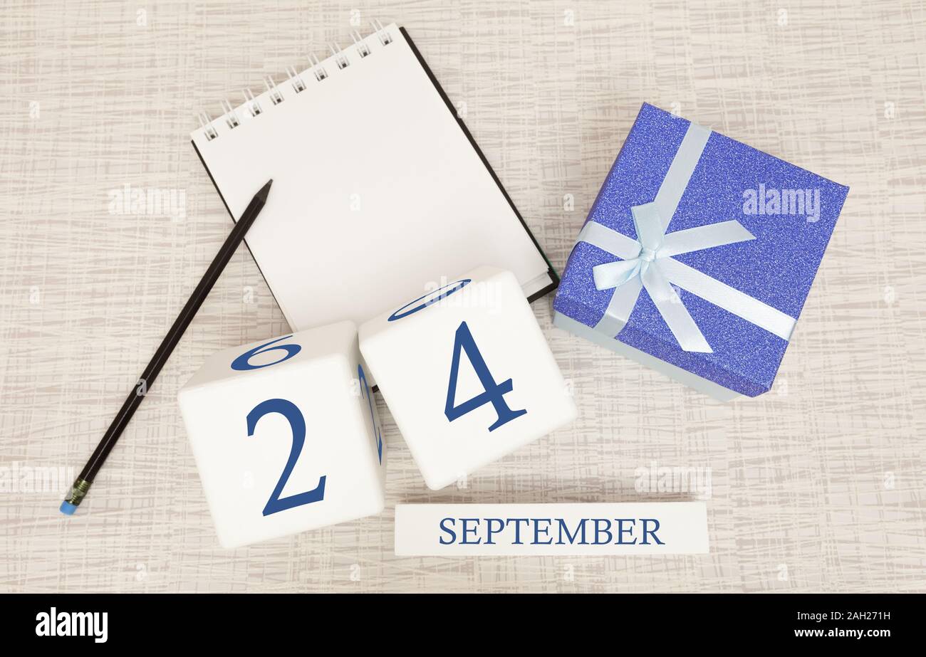 Gift box and wooden calendar with trendy blue numbers, September 24, business planner Stock Photo