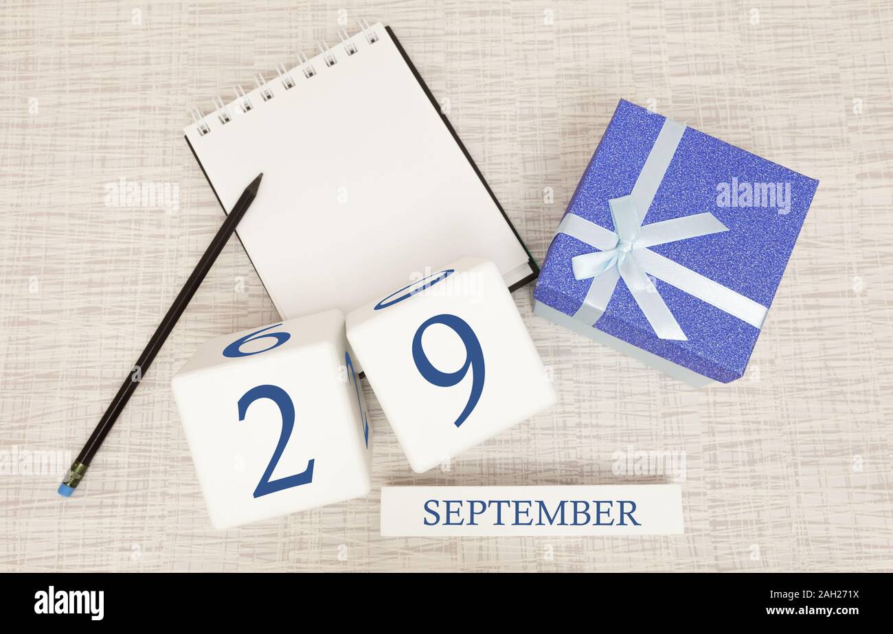 Gift box and wooden calendar with trendy blue numbers, September 29, business planner Stock Photo