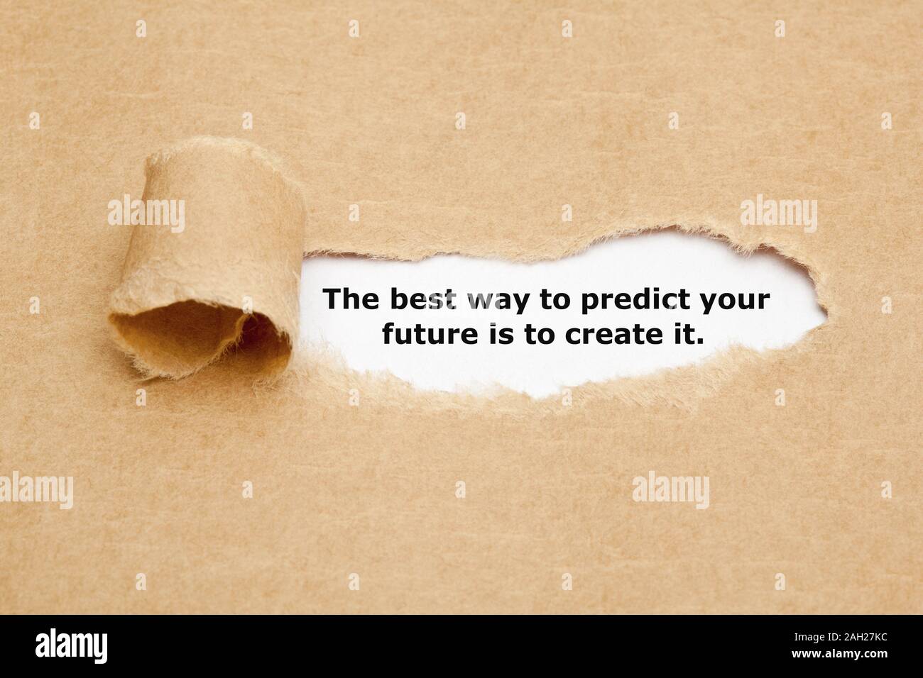 Inspirational quote The best way to predict your future is to create it. appearing behind torn brown paper. Stock Photo