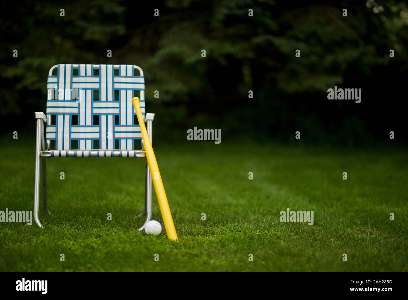 Lawn chair, baseball bat and ball in a backyard Stock Photo Alamy