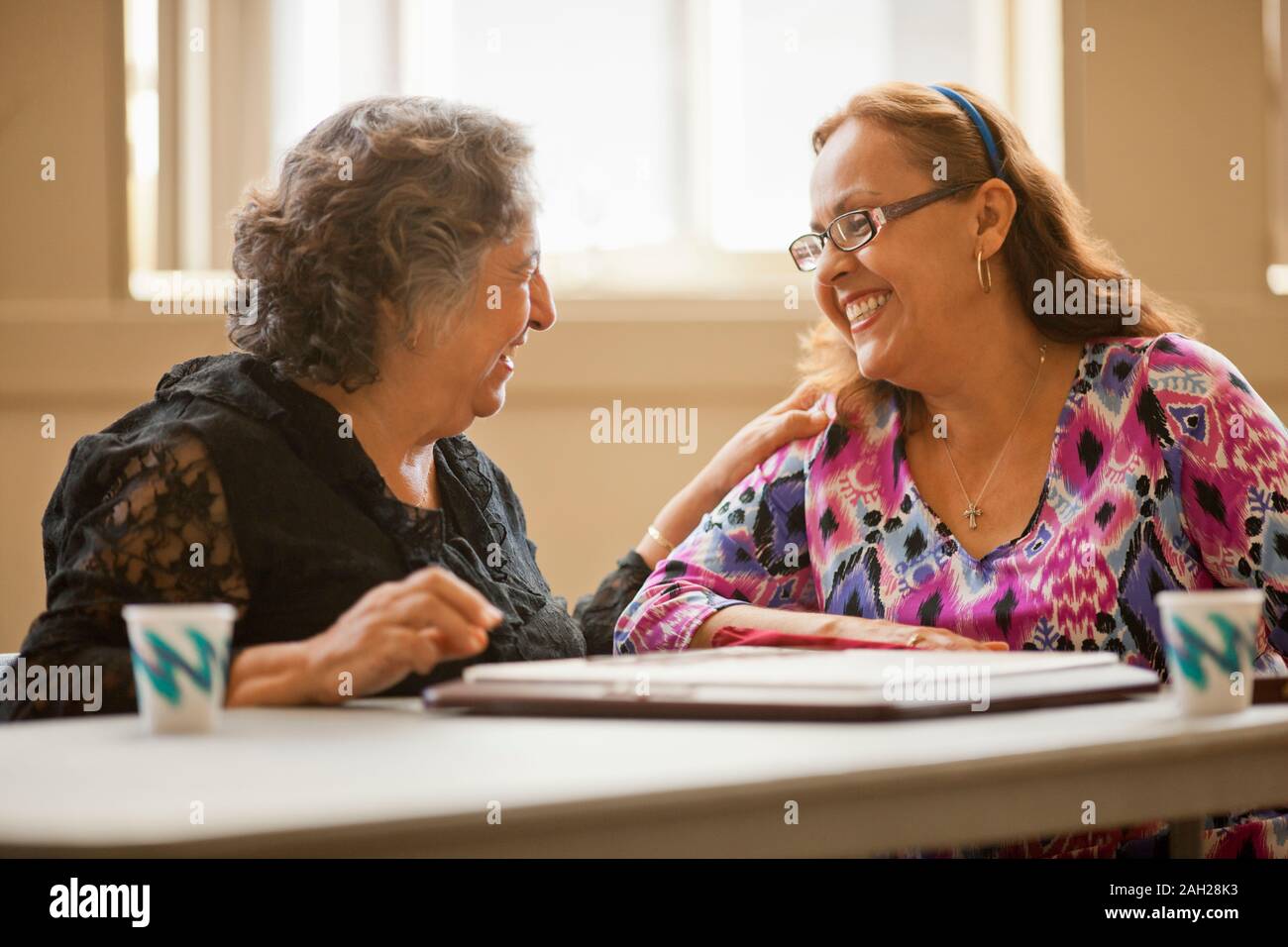 Two happy senior women playing a board game together at a table. Stock Photo