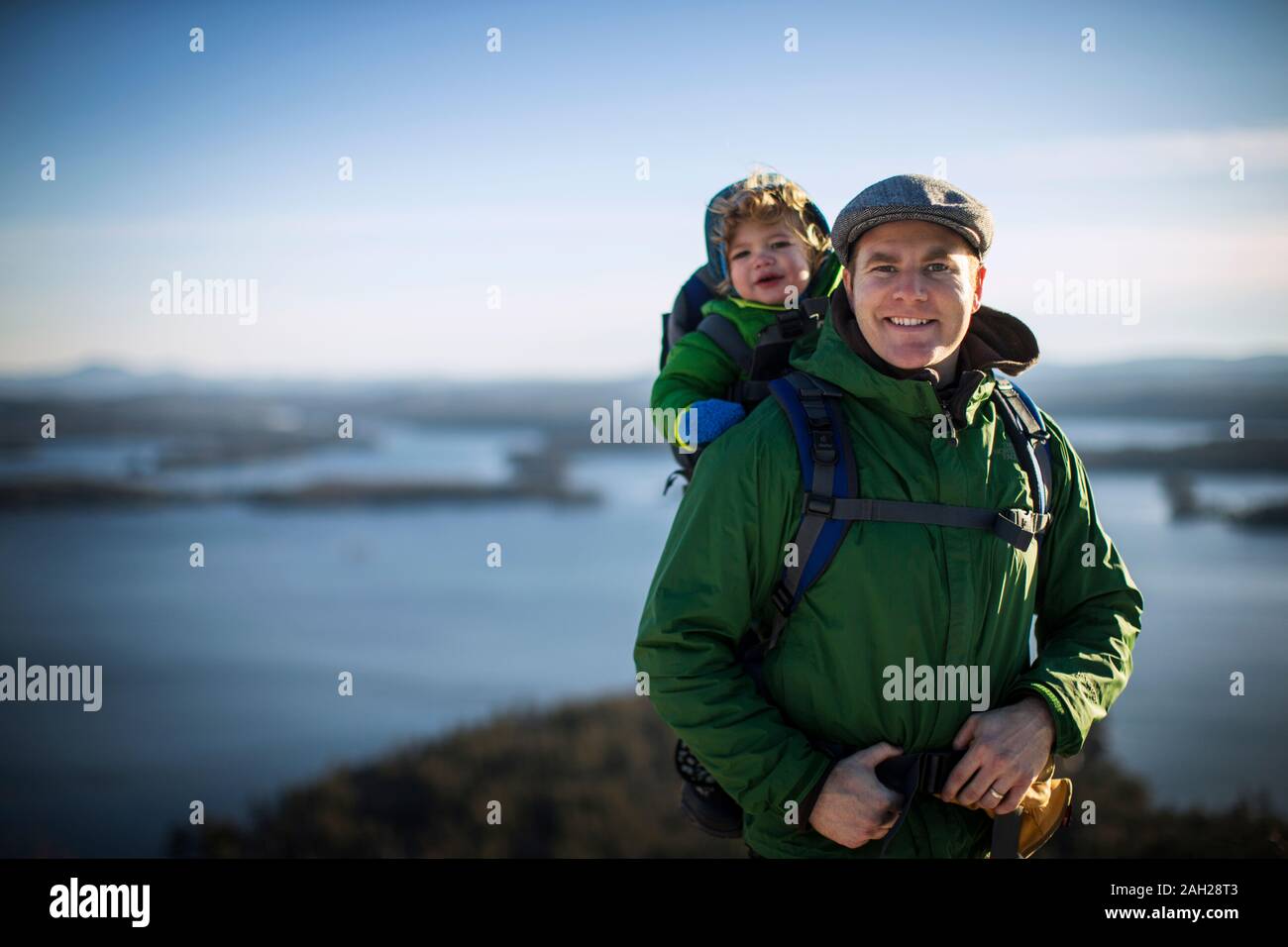 Portrait of a smiling mid adult man sitting on a rock with his young ...