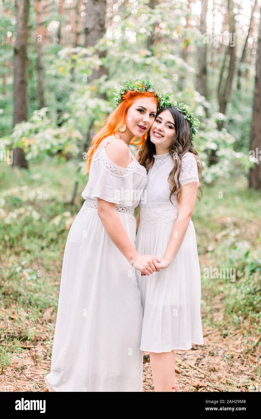 Two beautiful stylish happy bridesmaids in white dresses and wreaths on ...