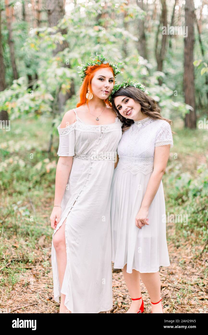 Beautiful two girls bridesmaids in white d.resses and floral wreaths on ...