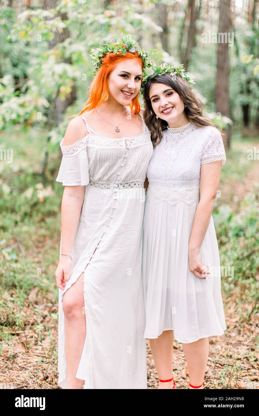 Beautiful two girls bridesmaids in white d.resses and floral wreaths on ...