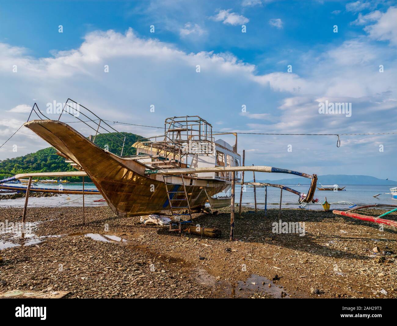 A Filipino wooden outrigger boat, locally known as a banca, under construction on an island beach at low tide. Bancas are used for interisland travel. Stock Photo