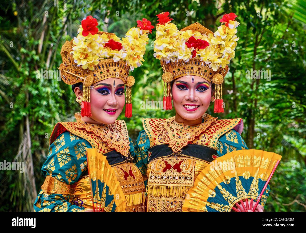 The ornate costumes, face makeup, and flower headdresses of traditional kecak fire dancers as they prepare for a cultural performance. Stock Photo