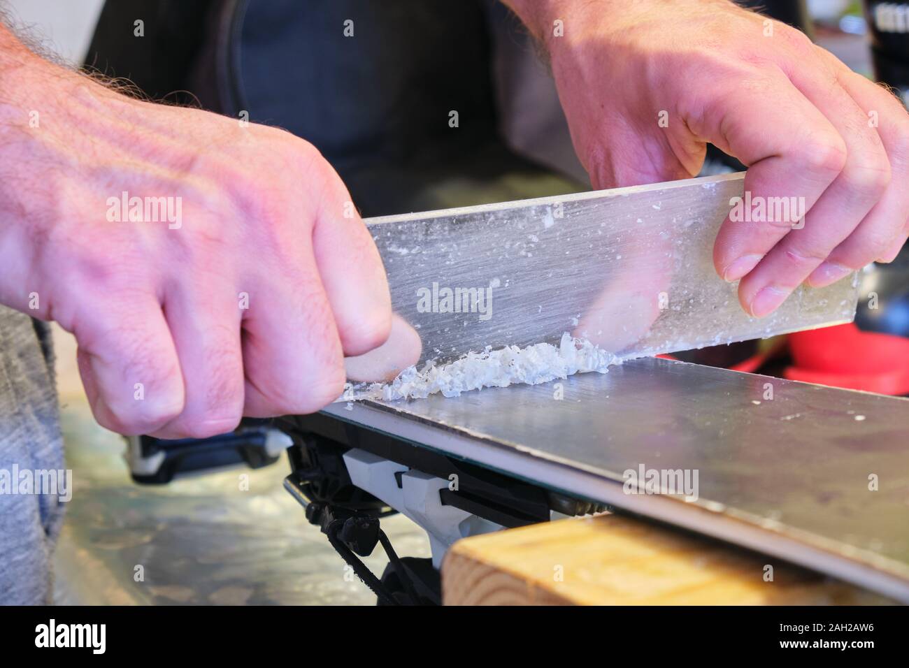 Removing excess wax from ski base using a plexi scraper focus on the