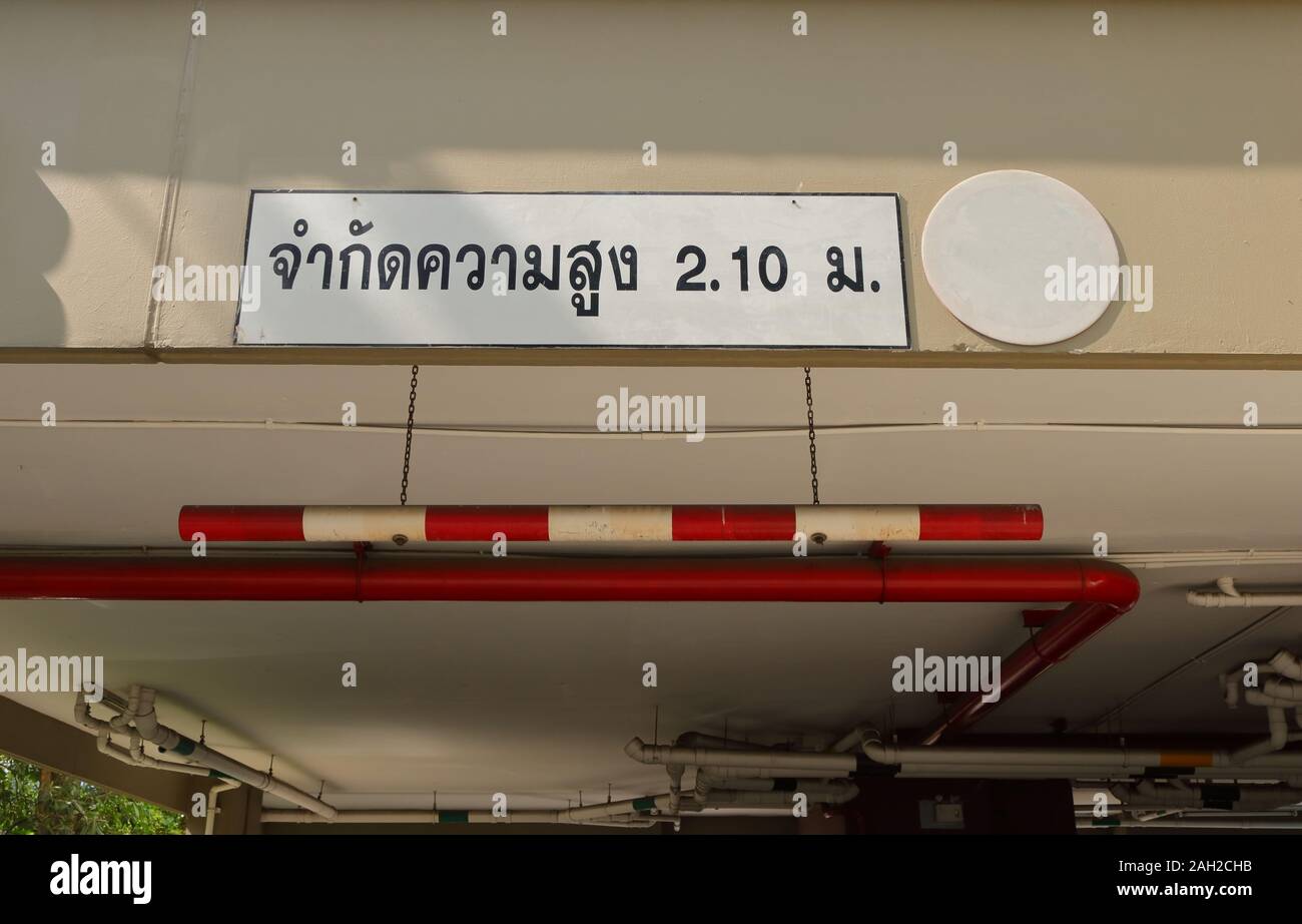 Car height limit sign made from PVC pipe painted with red and white, hanging from ceiling by chains, the Thai language means limit height 2.10 m Stock Photo