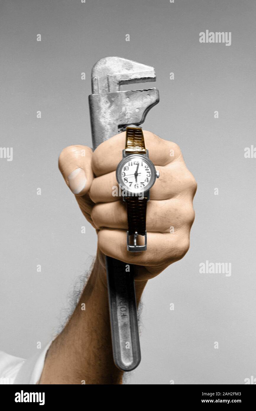 Fist holding wrench and watch Stock Photo