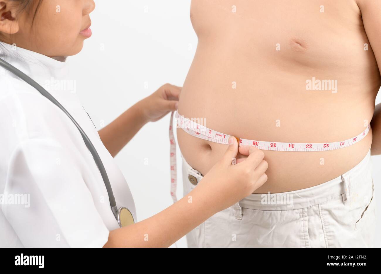 Little doctor measuring obese child waist body fat isolated on white background. Obesity and weight loss. Health care concept Stock Photo