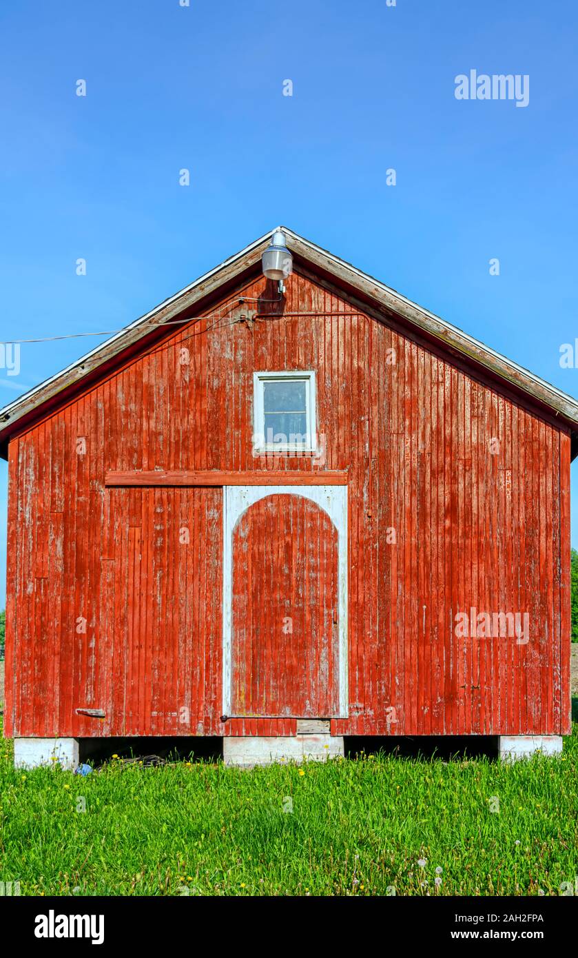 A red barn with weathered wooden exteriors illuminated by strong morning sunlight. Stock Photo