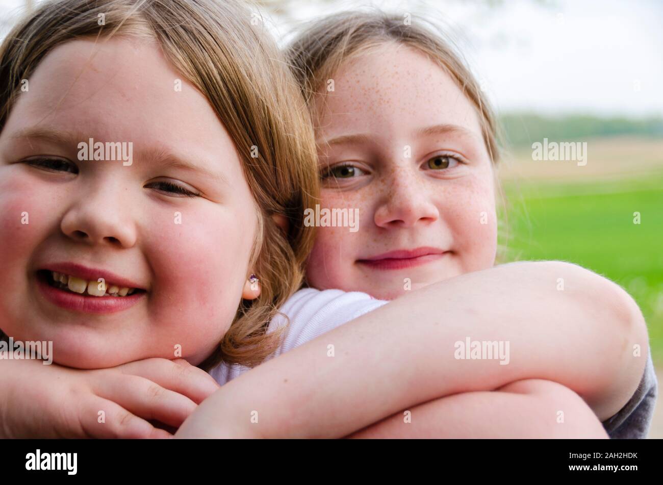 Two 10 year old girls hugging each other and smiling at the camera. Stock Photo