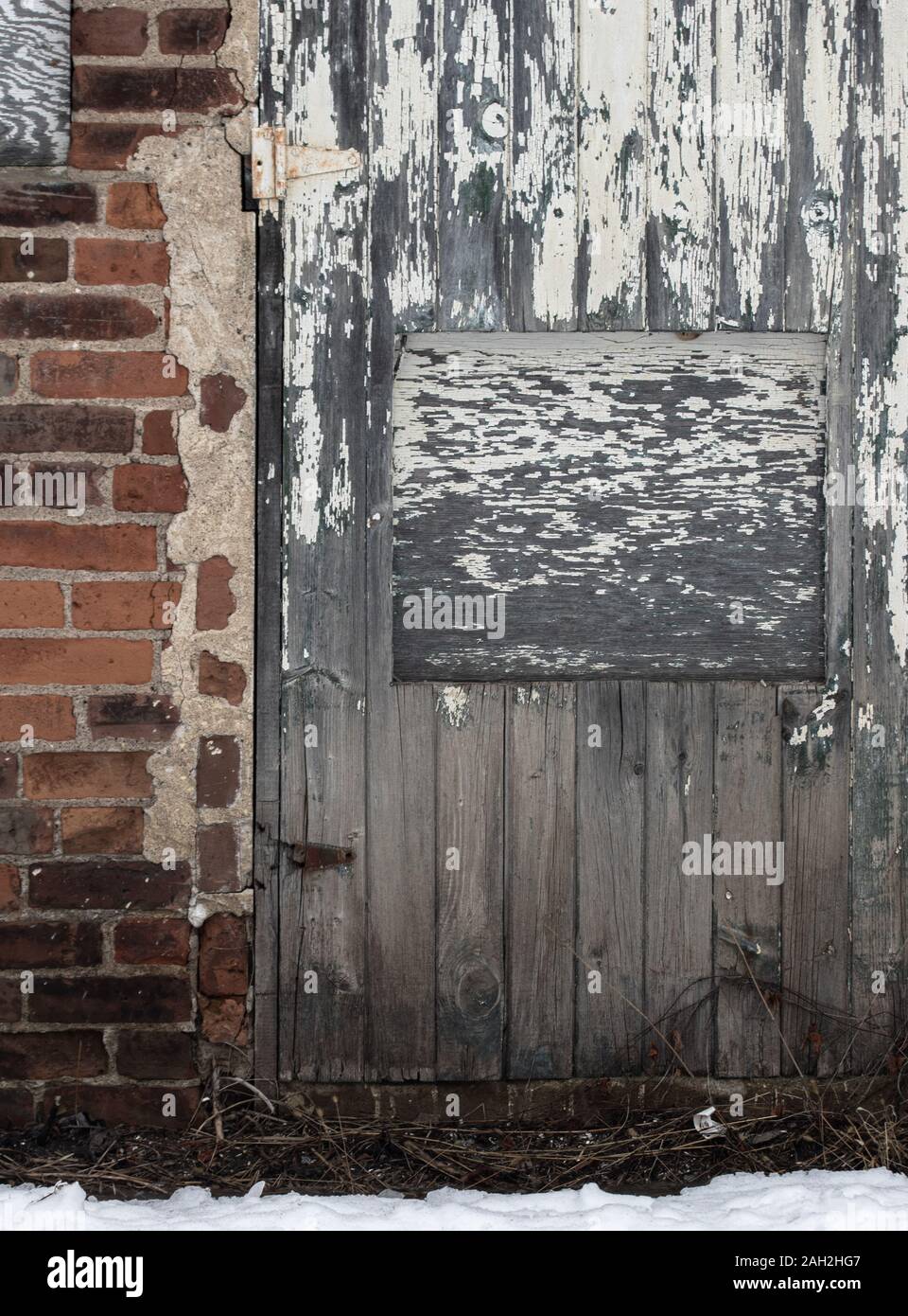 Old paint worn door and crumbling brick wall creating interesting textures Stock Photo