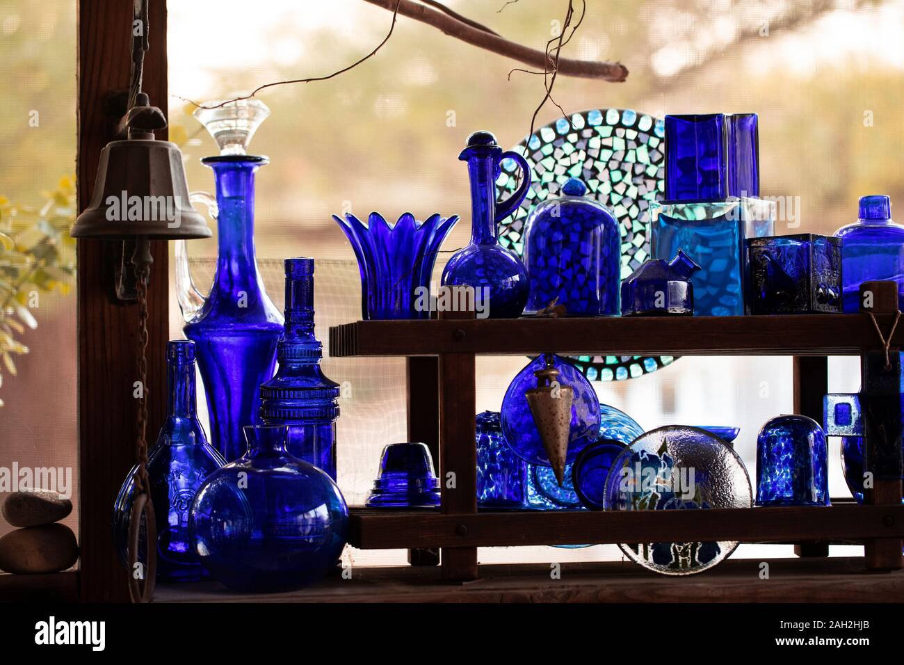 A collection of cobalt blue glass bottles and jars in a porch window in Indianapolis, Indiana, USA. Stock Photo