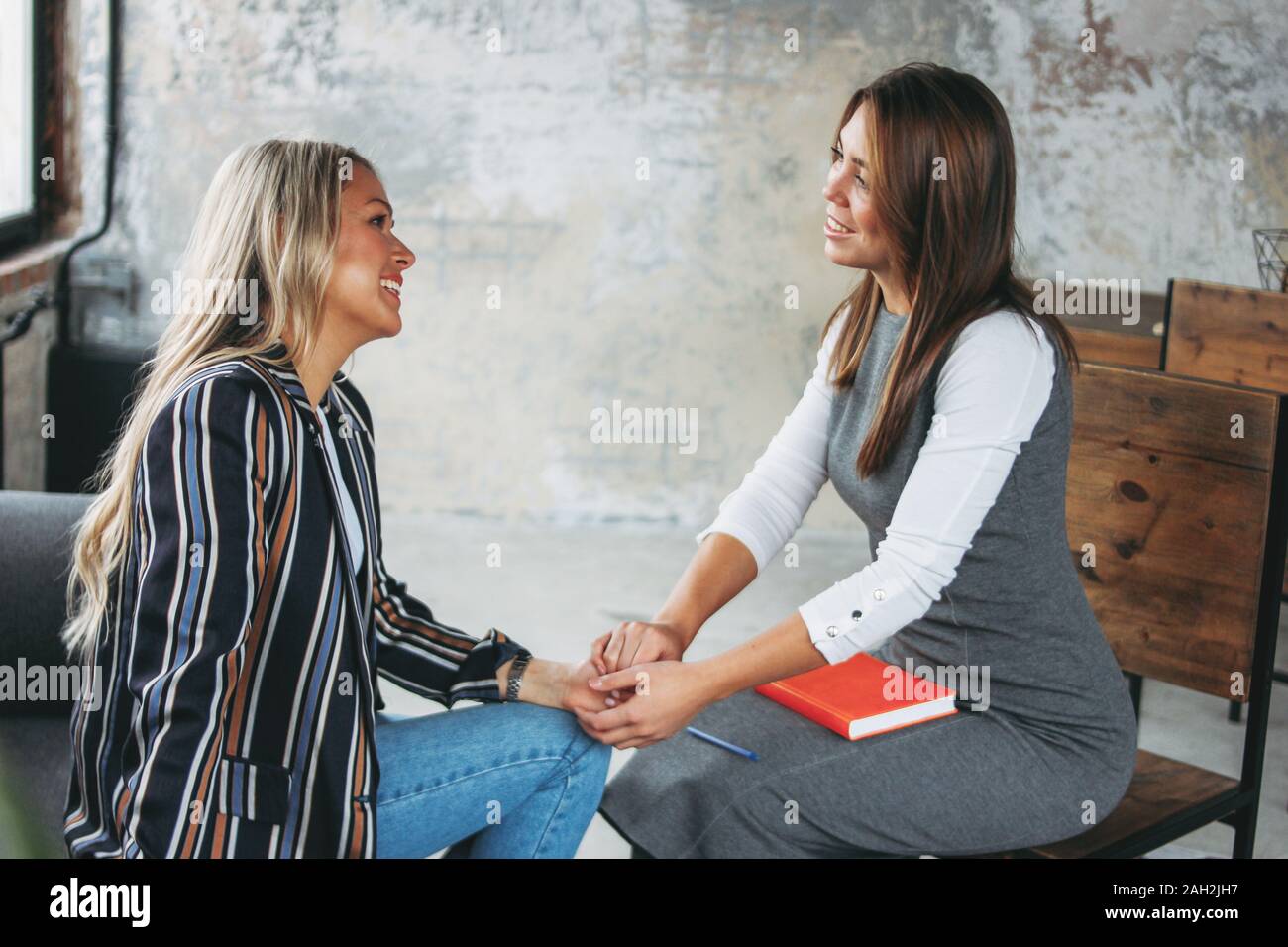 Young successful women colleagues discuss joint project, coaching or psychotherapy in the modern loft office Stock Photo