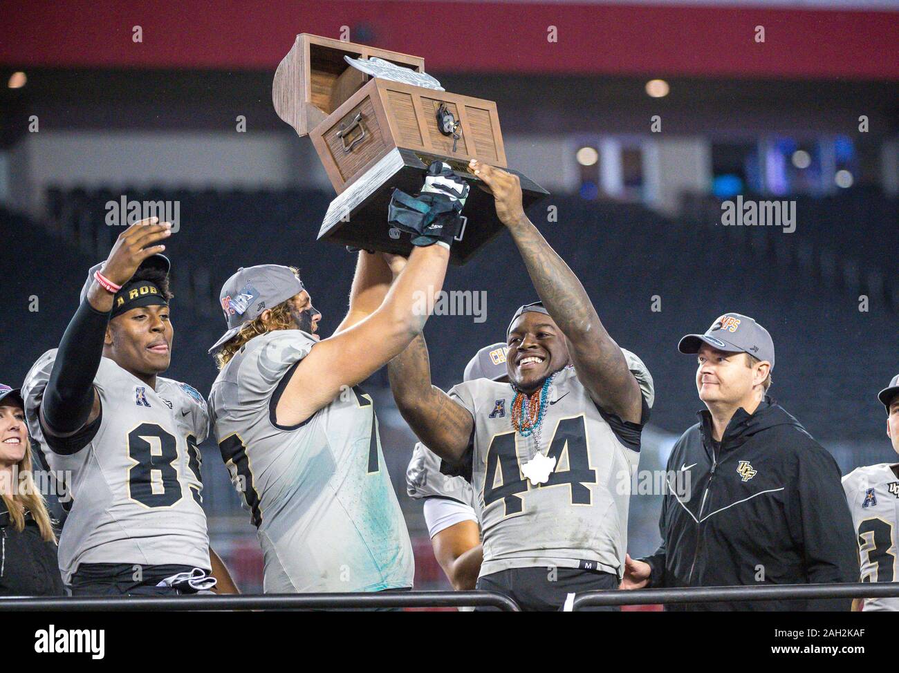 Tampa, FL, USA. 23rd Dec, 2019. (Right) UCF head coach Josh Heupel watches as the Gasparilla trophy is hoisted by L-R UCF tight end Anthony Roberson (89), UCF offensive lineman Jake Brown (77) and UCF linebacker Nate Evans (44) during awards ceremony of the Bad Boy Mowers Gasparilla Bowl between UCF Knights and the Marshall Thundering Herd. Central Florida defeated Marshall 48-25 at Raymond James Stadium in Tampa, FL. Romeo T Guzman/CSM/Alamy Live News Stock Photo