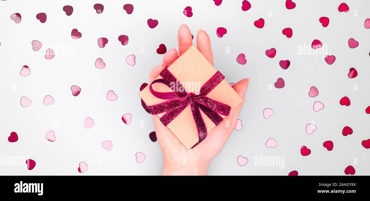 Craft box with dark red velvet ribbon bow in female hand. Valentine day ...