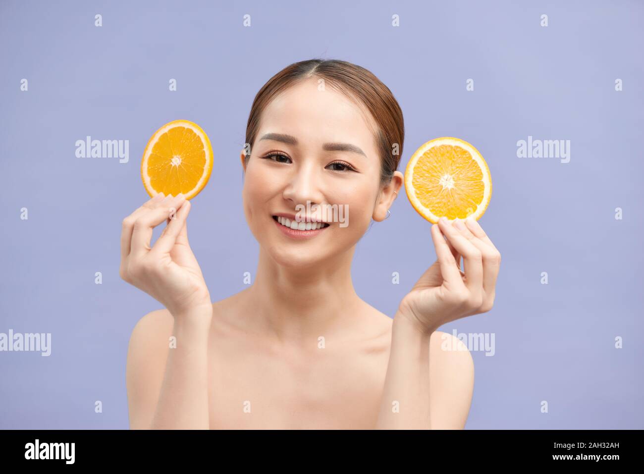 Smiling black haired model on white background holding orange slices Stock Photo